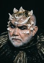 Evil underworld king with thorns on face and white beard wearing dark metallic outfit isolated on black background Royalty Free Stock Photo