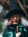 Evil witch on nature dark background, closeup portrait of old lady with terrifying makeup, Halloween background