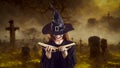 Evil witch reading her book of spells while standing in dark graveyard on Halloween Royalty Free Stock Photo