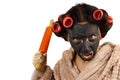 Evil young housewife in curlers and cosmetic face mask holding a rolling pin