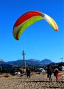 Paraglider landing on a beach with blue sky