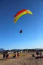 Paraglider landing on a beach with blue sky