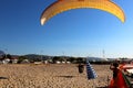 Paraglider landing on a beach with blue sky