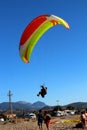 Paraglider landing on a beach with blue sky