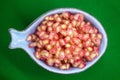 Pomegranate grains ready for healthy finger food served in a heavenly bowl on a green background Royalty Free Stock Photo