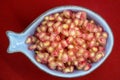 Pomegranate grains ready for healthy finger food served in a heavenly bowl on a red background Royalty Free Stock Photo