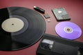 The evolution of recording and storing music and data, vinyl record, cassette, disk, hard drive, flash cards on a red-burgundy bac