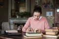 Exam preparation. Student girl in glasses and a pink sweater leaned over books, engaged in an old library at the table. Royalty Free Stock Photo