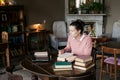 Exam preparation. Student girl in glasses and a pink sweater leaned over books, engaged in an old library at the table. Royalty Free Stock Photo