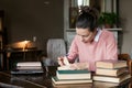 Exam preparation. Student girl in glasses and a pink sweater leaned over books, engaged in an old library at the table. Royalty Free Stock Photo