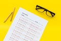 On the exam. Exam sheet, answer near glasses and pencil on yellow background top view Royalty Free Stock Photo