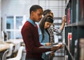 In exam time the library is your best friend. a group young students standing in a library picking out books to read.