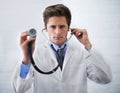 Examination time. a serious-looking doctor holding up the end of a stethoscope toward the camera. Royalty Free Stock Photo