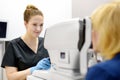 Examining of fundus of mature woman by female ophthalmologist using retinal scanner. Patient during visit to optometrist for