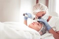 Dermatologist wearing mask and gloves examining the skin of client