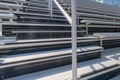 Close-Up of empty metal stadium bleacher seats along aisle with steps and railing. Royalty Free Stock Photo