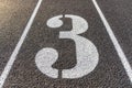 Close up lane number three, 3, on a new black running track with white lane lines and other markings Royalty Free Stock Photo