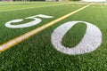 Synthetic turf football field fifty, 50, yard line in white. Royalty Free Stock Photo
