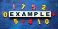 EXAMPLE word written on a wooden block against the background of a school board