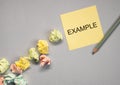Example word on yellow sticky note on grey background with crumpled papers Royalty Free Stock Photo