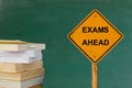 EXAMS AHEAD word on traffic sign with books and blackboard Royalty Free Stock Photo