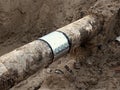 Excavation pit. Old drink water pipe with stainless repairing sleeve members. Royalty Free Stock Photo