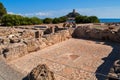 Excavations in Nora, Sardinia - old stone mosaic with remnants of walls and in the background a hill with a watchtower