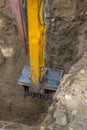 Excavator arm digging deep hole seeking cracked sewage pipe