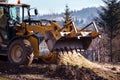 The excavator backfills the pit with the front bucket and moves soil around the construction site. Close-up. Heavy