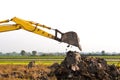 Excavator backhoe arm with a bucket is working in the digging a soil to adjust the postharvest areas in the rice fields.