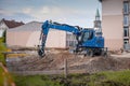 Excavator or backhoe on a construction site in the city. Blue digger resting on a pile of dirt or gravel while making base plate