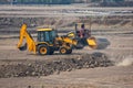 Excavator Backhoe Digger Loader leveling the field with Road Roller at Construction Site Royalty Free Stock Photo