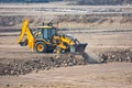 Excavator Backhoe Digger Loader leveling the field with road roller at Construction Site Royalty Free Stock Photo