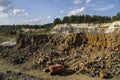 Excavator and basalt columns rocks. Heavy industry. Stone excavation. Producing stone from basalt pillars. Royalty Free Stock Photo