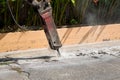 Excavator breaking and drilling the concrete road for repairing. Large pneumatic hammer mounted on the hydraulic arm of a construc Royalty Free Stock Photo