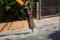 Excavator breaking and drilling the concrete road for repairing. Large pneumatic hammer mounted on the hydraulic arm of a construc