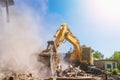 Excavator breaks old house, many dust in air. Building demolition and deconstruction, copy space