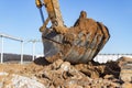 Excavator bucket close-up against the blue sky digs the ground. Earthworks with heavy equipment at the construction site Royalty Free Stock Photo