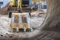 Excavator bucket close-up against the blue sky digs the ground. Earthworks with heavy equipment at the construction site Royalty Free Stock Photo