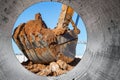 Excavator bucket close-up against the blue sky digs the ground. Earthworks with heavy equipment at the construction site Royalty Free Stock Photo