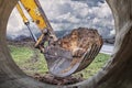 Excavator bucket close-up against the blue sky digs the ground. Earthworks with heavy equipment at the construction site Royalty Free Stock Photo