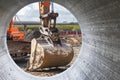 Excavator bucket close-up view from a large diameter pipe. Heavy earthmoving equipment. Soil development. Laying of underground Royalty Free Stock Photo