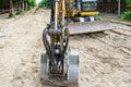 Excavator bucket closeup at street reconstruction site, dismantled street surface