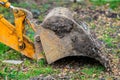 Excavator bucket digging earth in green field with fallen leaves Royalty Free Stock Photo