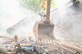 Excavator bucket in dust. Building demolition. Structure dismantling Royalty Free Stock Photo