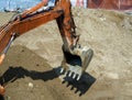 The excavator bucket is lowered into the pit to pick up the soil from there. Close-up. Background with a construction site