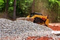 An excavator bucket rakes in crushed stone the excavator is picking up a full bucket