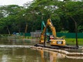 An excavator / bulldozer performing dredging work in a canal / river in a tropical rainforest / jungle habitat in Singapore, South