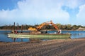 Excavator for channel dredge on a barge