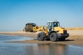 Excavator cleaning a beach from seaweed